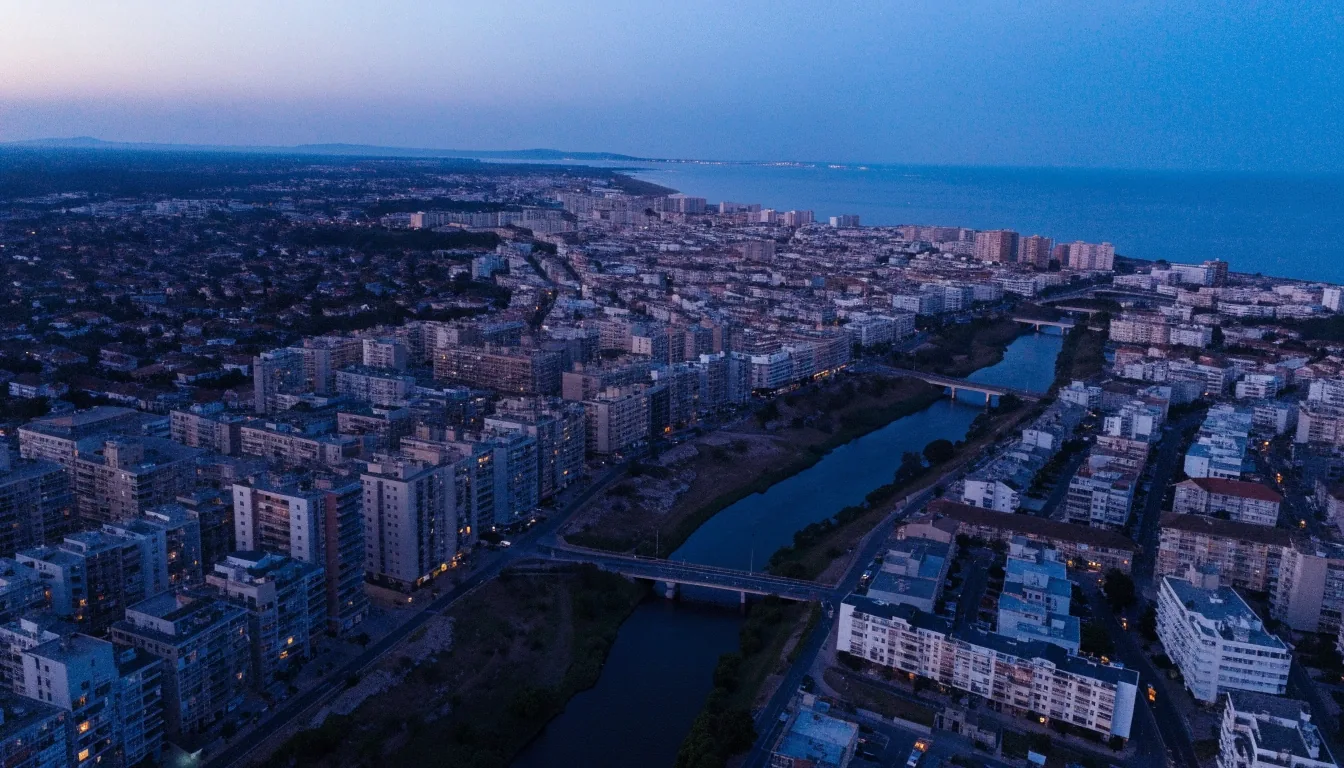 Vista aérea al atardecer de una gran área urbana española, con barrios densos, un río y vías de tráfico iluminadas